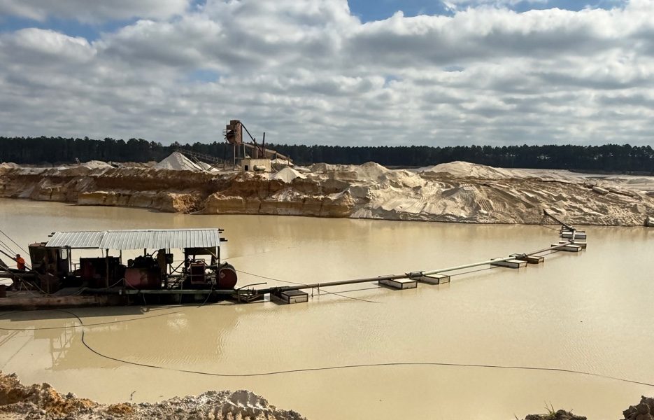A dredge and discharge line on the water with the wash plant on the horizon at a Crawford Aggregate mine